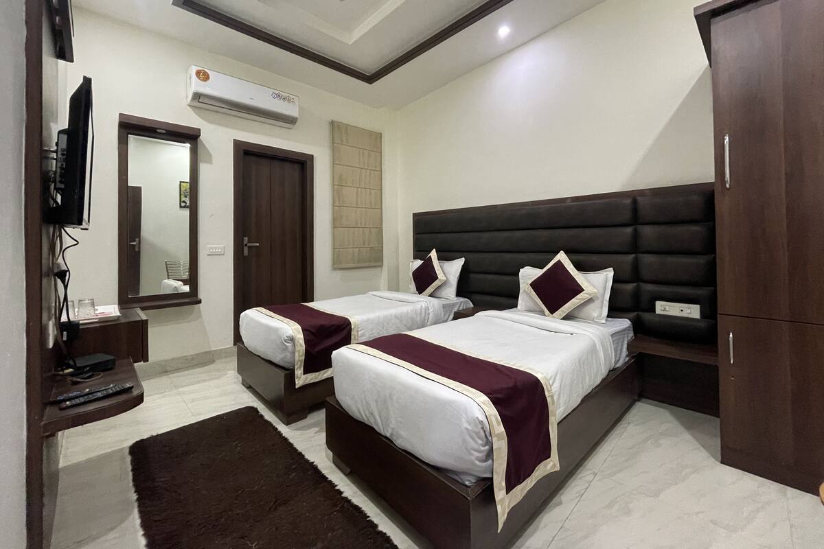 Quarto de hotel com duas camas, televisão, ar condicionado e guarda-roupa.