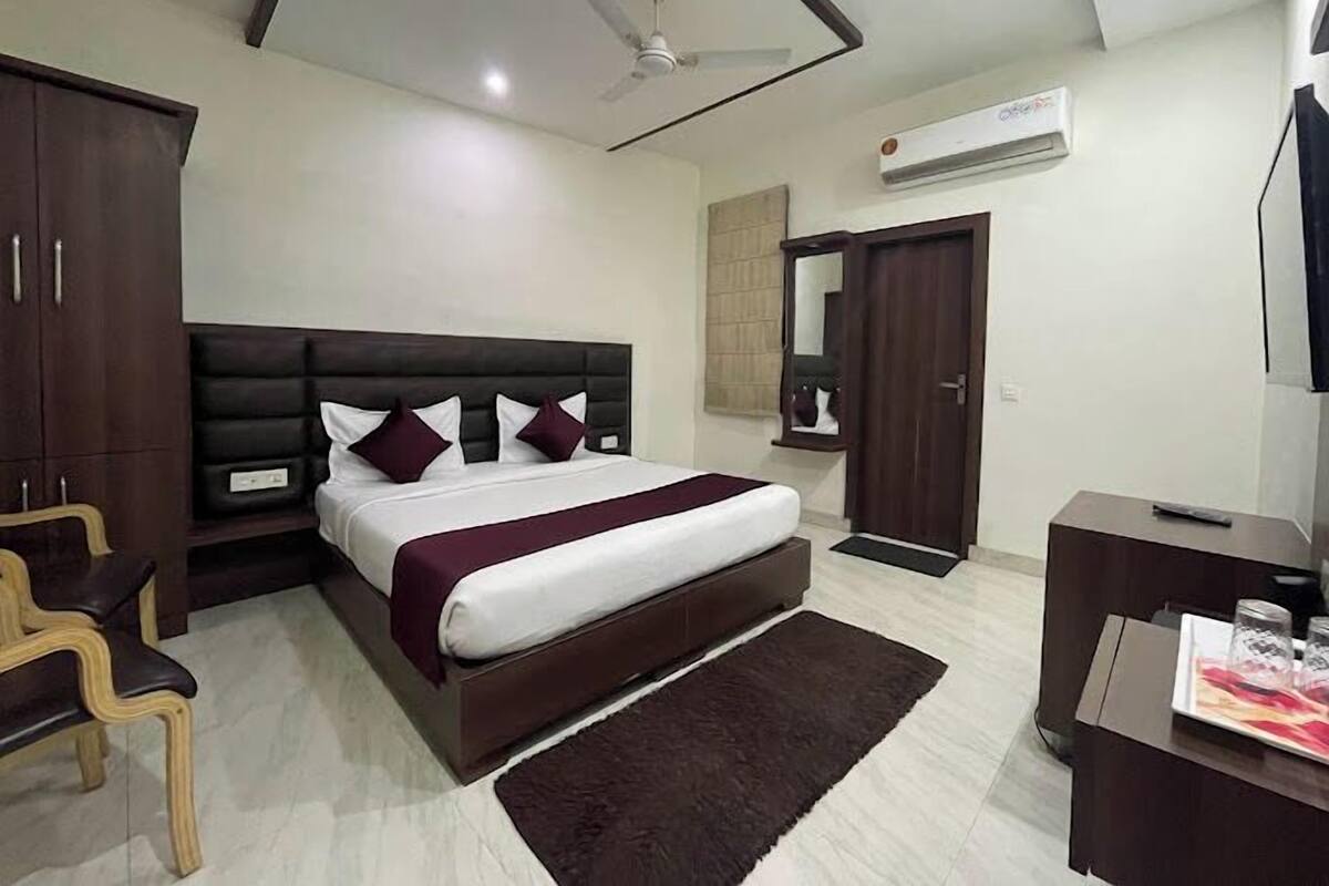 Quarto com cama, mesa de cabeceira, guarda-roupa, espelho, ventilador de teto e ar-condicionado.