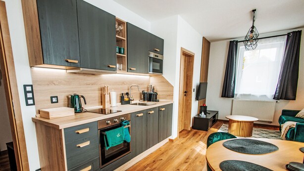 Een moderne keuken met donkere kastjes, een houten aanrechtblad en een inbouwoven.