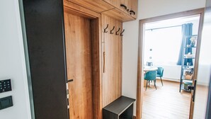 Een modern appartement met een houten garderobe, een bankje en uitzicht op een balkon met een stoel en een tafel.