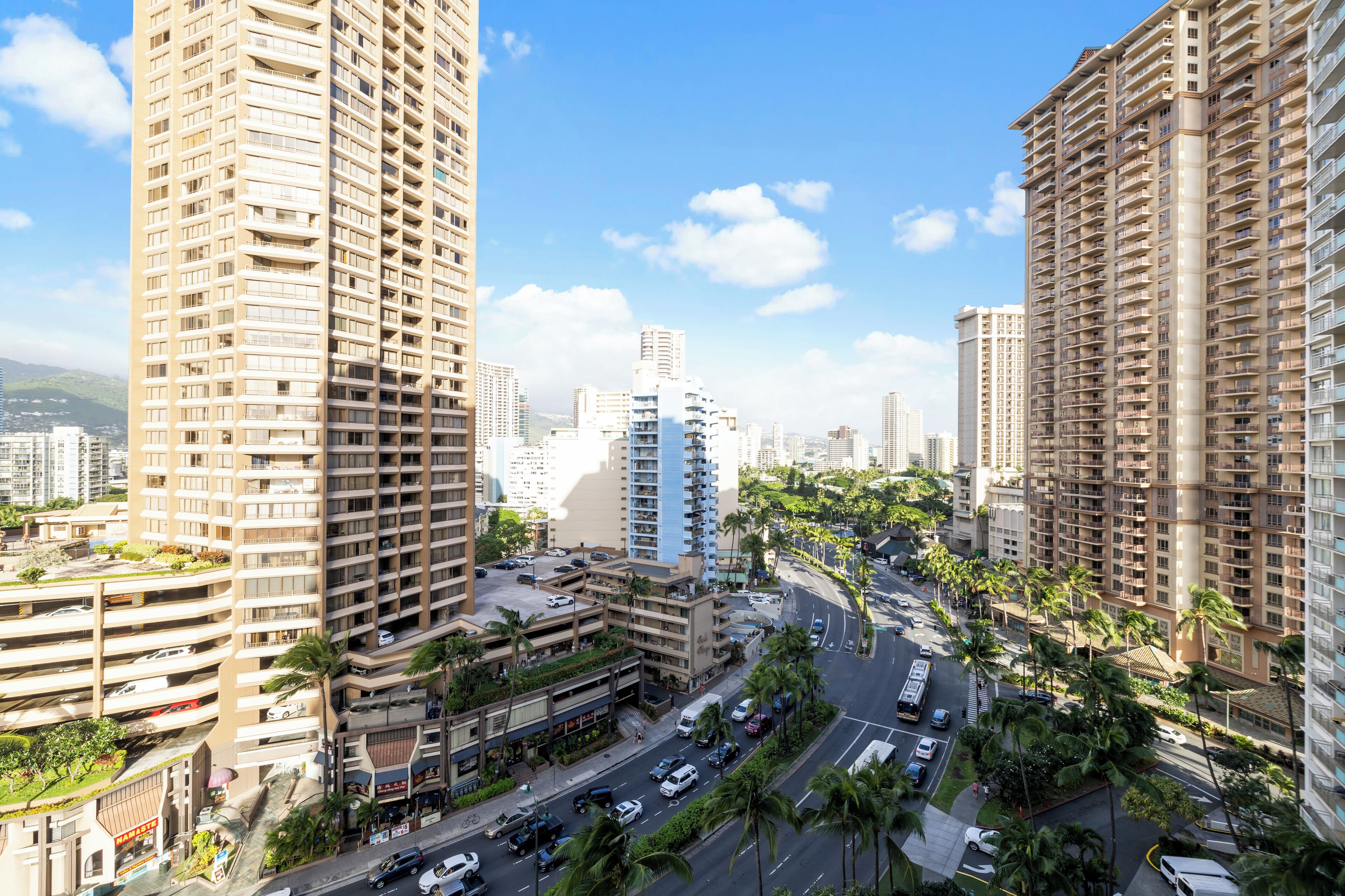 A high-rise urban area with multiple buildings, roads, and palm trees.