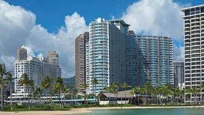 A beachfront hotel with multiple high-rise buildings, palm trees, and a sandy beach. - Ilikai Hotel Studio (Honolulu)