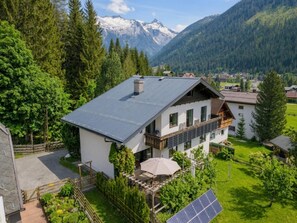 Een tweelaags huis met schuin dak, een balkon en een zonnepaneel.