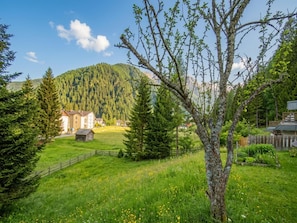 Un paysage rural avec un bâtiment entouré d’arbres et une montagne en arrière-plan.