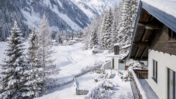 Paisaje nevado de una montaña con un edificio de madera que tiene ventanas amplias y un techo inclinado.