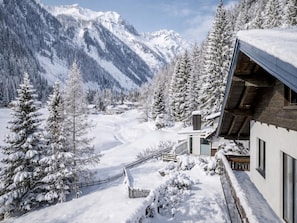 Un paysage montagneux enneigé avec un bâtiment en bois doté de grandes fenêtres et d’un toit en pente.