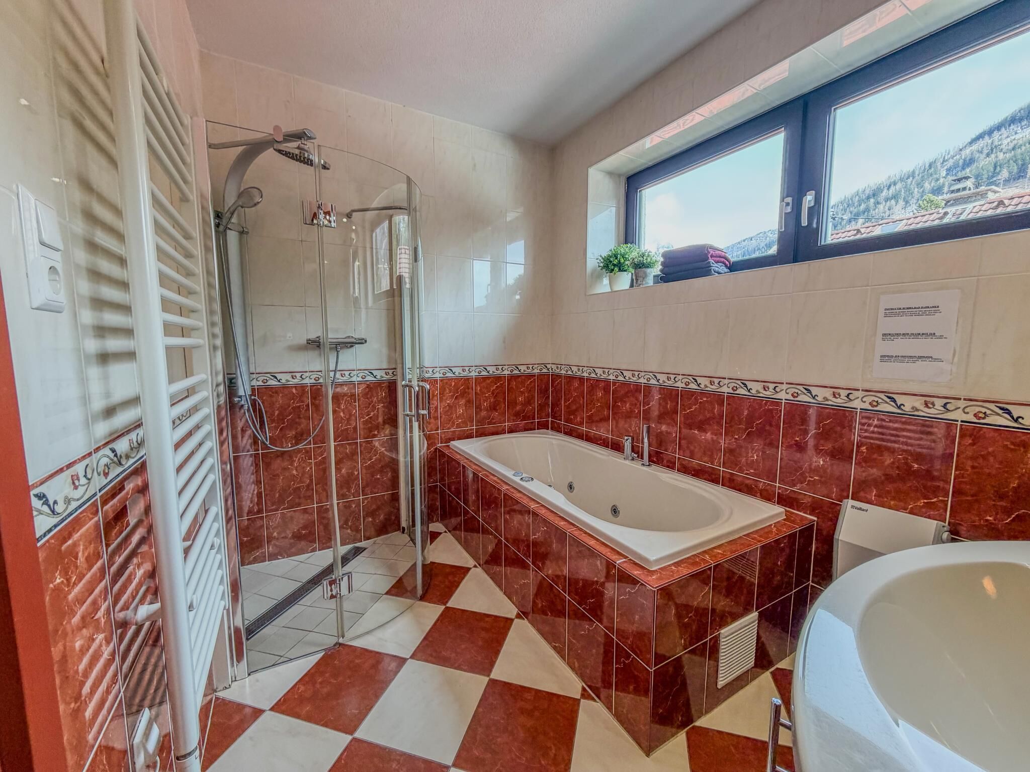 A bathroom with a glass-enclosed shower, a freestanding bathtub, and a window with a view.