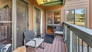 Eine überdachte Terrasse im Freien mit zwei Stühlen, einem Tisch und Blick ins Innere.