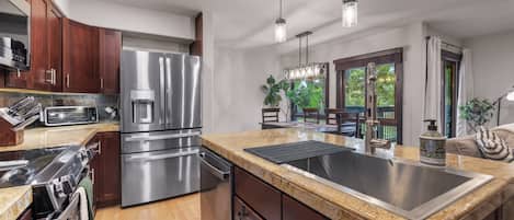 A modern kitchen with stainless steel appliances, a large island, and pendant lighting.