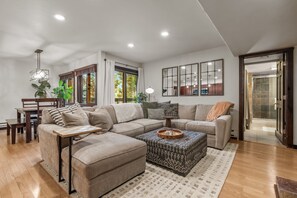 Un salon moderne avec un canapé d’angle, une table basse et un coin repas comprenant une table et des chaises en bois.