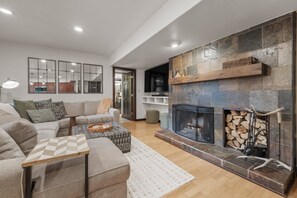 Un salon moderne avec une cheminée, un ensemble de canapés, une table basse et une table à manger.