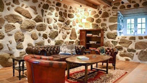 A stone-walled room with leather furniture, a wooden coffee table, and a bookshelf. - Lovely home in Sallerup with WiFi (Sallerup)