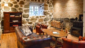 A cozy living room with a stone wall, leather sofa, and a fireplace. - Lovely home in Sallerup with WiFi (Sallerup)