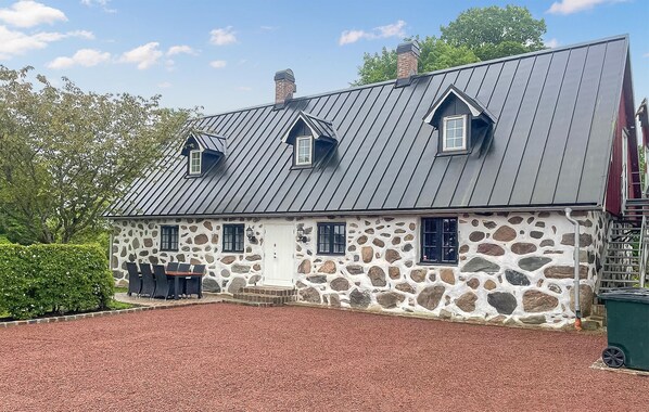 A stone house with a metal roof and two dormer windows.