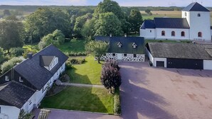 An aerial view of a rural property with a large white building, a stone structure, and a tree in the center. - Lovely home in Sallerup with WiFi (Sallerup)