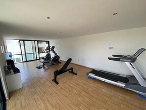 Ein Fitnessraum mit Cardiogeräten, einer Bank und einem Laufband.