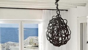 Un comedor con una mesa y sillas de madera, una lámpara colgante y vistas al mar a través de amplios ventanales.