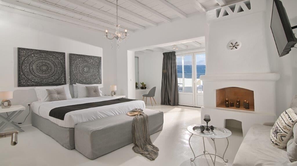 A modern bedroom with a large bed, a fireplace, and a balcony with a view.