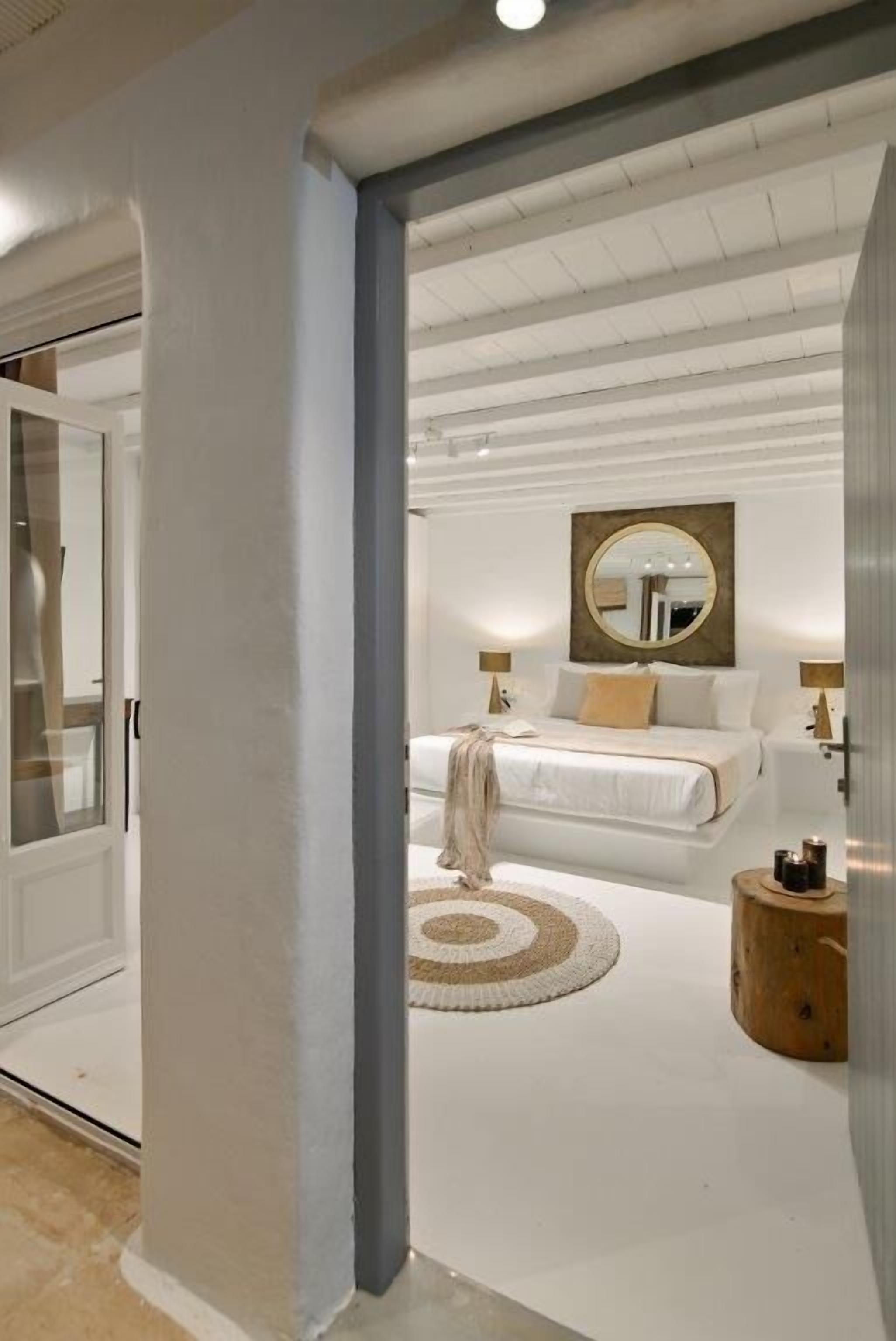 Ein modernes Schlafzimmer mit einem großen Bett, einem runden Spiegel und einem Holznachttisch.