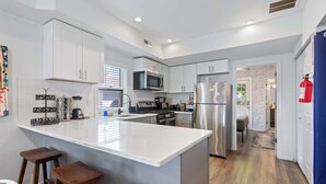 A modern kitchen with white cabinets, stainless steel appliances, and a central island with stools.