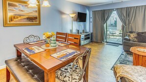 A dining area with a wooden table, chairs, and a bench. There is a television on the wall and a ceiling fan above. - Walk to Ocean: Myrtle Beach Townhome w/ Patio (Myrtle Beach)