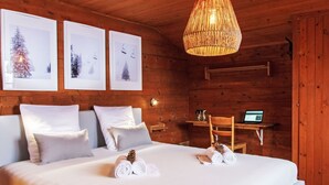 Un dormitorio de cabaña de madera acogedor, con una cama, almohadas, una lámpara colgante y cuadros en la pared.