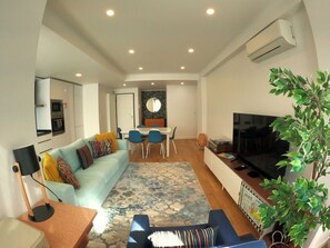 A modern living room with a sofa, TV, and dining area.