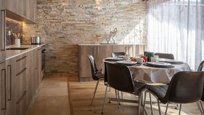 A modern kitchen with a stone backsplash, wooden cabinets, and a dining area with a table set for two.