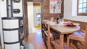 Un'accogliente sala da pranzo con un tavolo di legno apparecchiato per due persone, un camino a legna nero e un quadro appeso al muro.