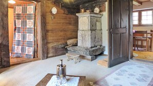 Una stanza rustica in legno con un camino in pietra, un cesto intrecciato e una bottiglia su un tappetino.
