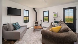 Un salón moderno con chimenea, televisor de pantalla plana y sofá con cojines.