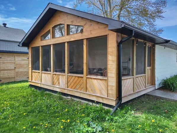 Een houten hut met grote ramen, een schuine kap en een overdekte veranda.