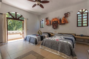 A hotel room with two beds, a ceiling fan, and a view of the outdoors.