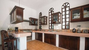 A kitchen with a central island, dark wooden cabinets, a stainless steel stove, and a tiled backsplash. - Casa Bravo - Garden Oasis Steps from la ropa (Zihuatanejo)