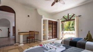 A hotel room with a bed, a desk, a chair, and a view of the outdoors. - Casa Bravo - Garden Oasis Steps from la ropa (Zihuatanejo)