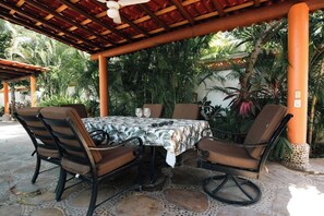 Un patio al aire libre con una mesa redonda, cuatro sillas y un ventilador de techo.