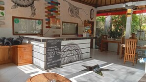 A restaurant with a central counter, wooden furniture, and decorative wall art. - Ratu Cottage by OurStory Travels (Penida Island)