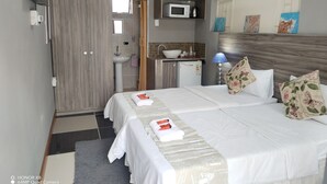 Hotellihuone, jossa on sänky, yöpöydät, pesuallas, mikroaaltouuni ja vaatekaappi.