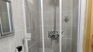 Kylpyhuone, jossa on suihku, pesuallas ja peili.