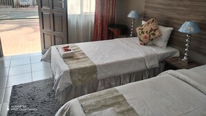 Hotellihuone, jossa on kaksi sänkyä, suuri ikkuna ja näkymä ulos kadulle.