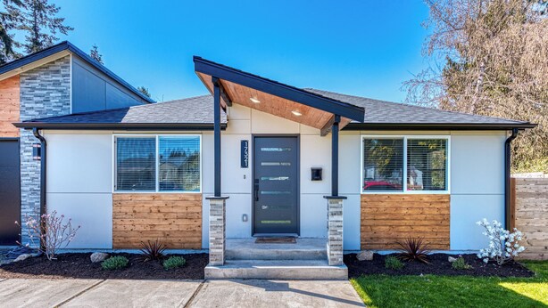 A modern two-story house with a front porch, a black door, and a small garden area. - Cozy Air-conditioned Retreat 3 mins from Airport (SeaTac)
