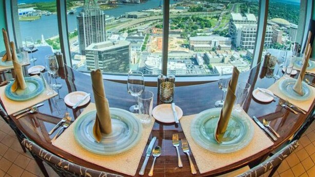 A dining area with a panoramic view of a cityscape and the sea. - Beautiful 1 BR Renovated Apt in downtown (Mobile)