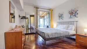 A bedroom with a metal bed frame, a wooden dresser, a mirror, and a door leading to another room. - Gorgeous apartment in Casarza Ligure with WiFi (Casarza Ligure)