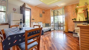 A cozy dining area with a table set for two, a sofa, and a wooden cabinet. - Gorgeous apartment in Casarza Ligure with WiFi (Casarza Ligure)