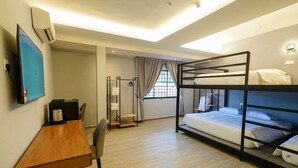 Une chambre avec des lits superposés, un bureau, une chaise, une télévision et une fenêtre avec des rideaux.