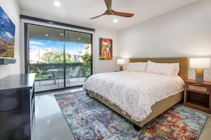 Un dormitorio con una cama grande, un escritorio y vistas al exterior a través de un ventanal corredero.