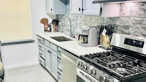 A modern kitchen with stainless steel appliances, grey cabinets, and a herringbone-patterned floor. - Sports Themed 3-Bedroom Home in Arlington near AT & T Stadium & Other Sports  (Arlington)