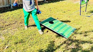 A child playing football in a backyard with a green field, a wooden fence, and a goalpost. - Sports Themed 3-Bedroom Home in Arlington near AT & T Stadium & Other Sports  (Arlington)