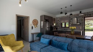 Ein modernes Wohnzimmer mit einer Couch, einem gelben Sessel und einem Essbereich mit Tisch und Stühlen.