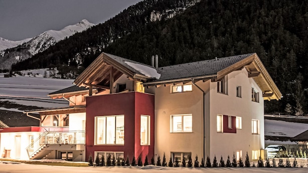 A two-story house with a balcony, surrounded by snow and mountains.